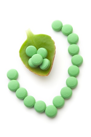 Green pills and a leaf on whiteの写真素材