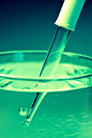 Medicine eyedropper in liquid with green lightの写真素材