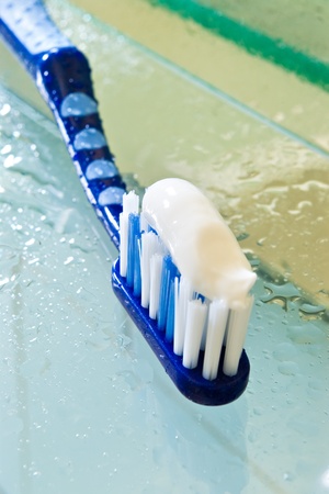 blue toothbrush with white paste in bathroomの写真素材