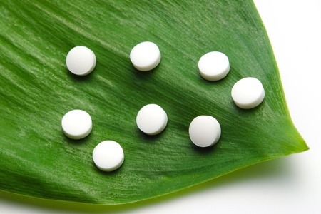 white pills on a green leaf, natural medicine conceptの写真素材