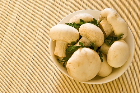 Mushrooms with parsley in white bowl on bamboo boardの写真素材