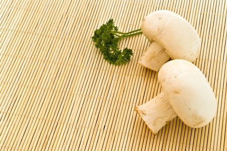 two mushrooms and parsley on bamboo boardの写真素材