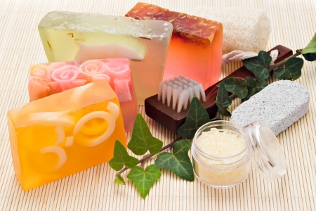 four handmade soaps with loofah brush and sea-salt on bamboo boardの写真素材