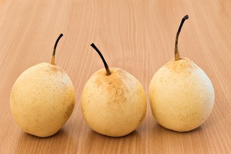 three golden pears on wood tableの写真素材
