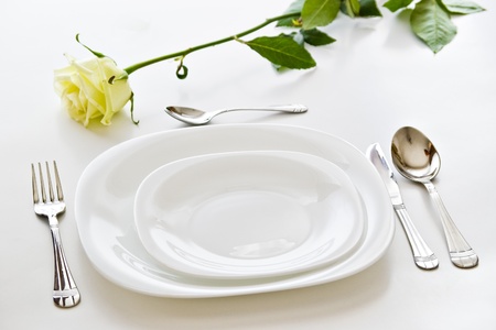 place setting with white plates and beige  rose flowerの写真素材