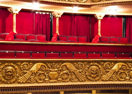 classic theatre balcony with red chairs and golden details