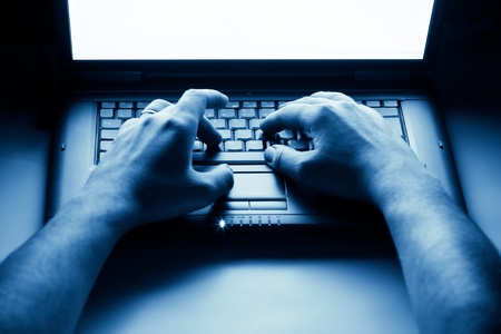male hands typing on laptop keyboard - blue toned