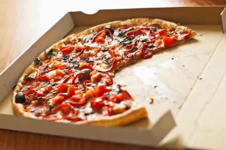 pizza without a slice in cardboard box on tableの写真素材