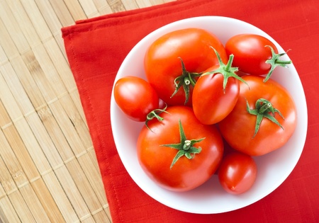 fresh tomatoes in white bowl on red napkin from aboveの写真素材
