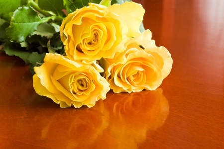 three yellow roses on wood tableの写真素材