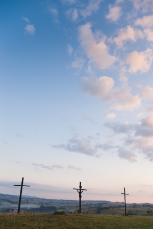 three crosses on sky with clouds and village on hillsの写真素材