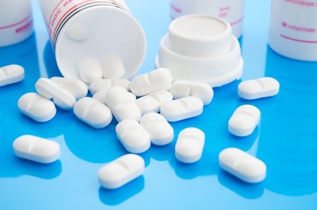 pills on blue with containers and shallow depth of field