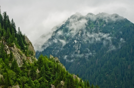 mountains peak through gray cloudsの写真素材