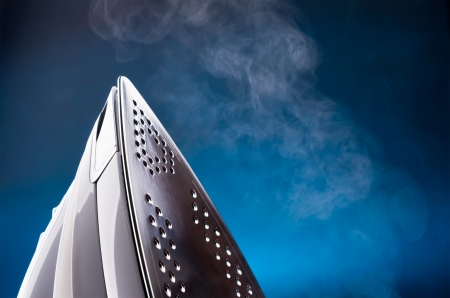 close up of ironing tool emitting steam on blueの写真素材