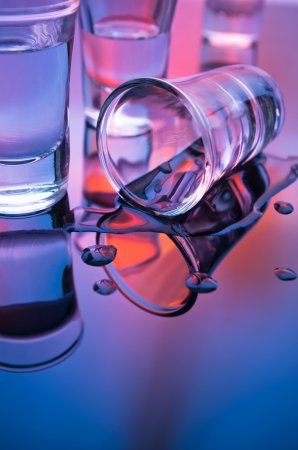 overturned shot glasses with reflection in mixed lightの写真素材