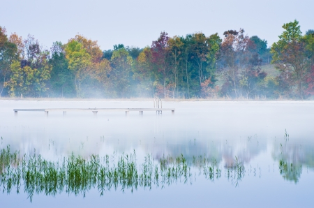 morning fog on lake with trees reflectionの写真素材