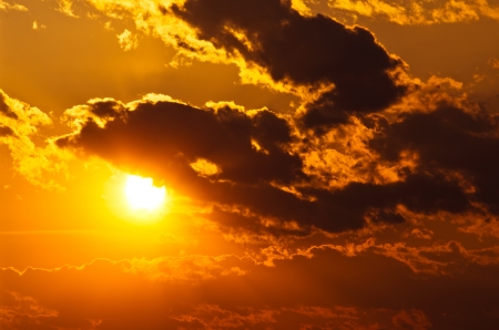 sun shining through clouds at sunsetの写真素材