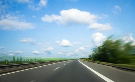 road with motion blur and blue sky with cloudsの写真素材