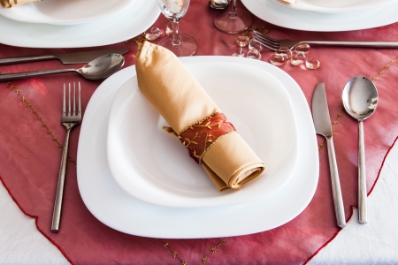 place setting with dark red napron and golden napkinの写真素材