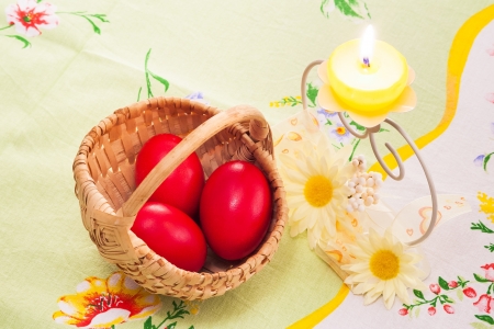 yellow candle and three red eggs in small basket for Easterの写真素材