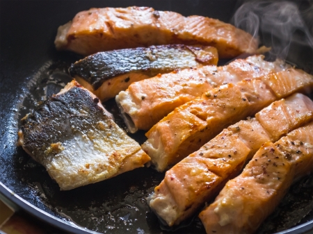 salmon slices in the frying panの写真素材
