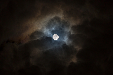 Full moon in a black and cloudy sky