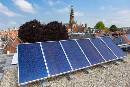 Solar panels on the roof in the South-Holland city of Leiden in the Netherlands. On the background the Hooglandse church.の写真素材