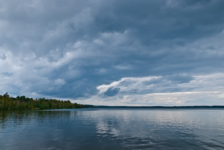 Dark clouds over the lake. Landscape with storm clouds.の写真素材