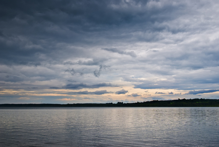 Dark clouds over the lake. Landscape with storm clouds.の写真素材