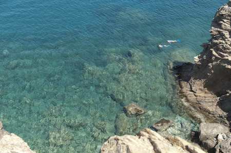 Two people snorkeling in the see close to the rocksの写真素材