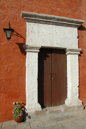 Old wooden door on an orange wall at Arequipa, Peruの写真素材