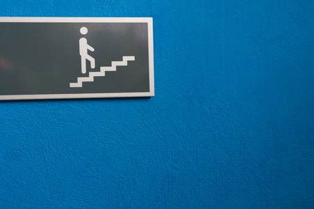 Sign showing character on stairs on blue wall.の写真素材