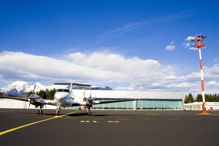 Small airplane on runway with hangar in background.の写真素材