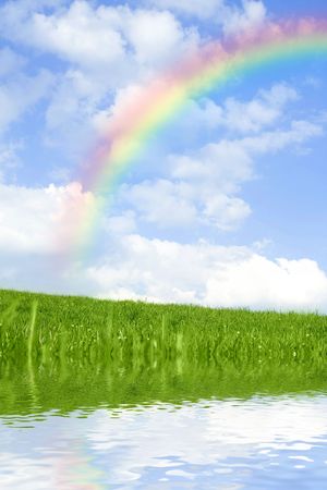 Beautiful green grass against blue sky and rainbow, with water reflection.の写真素材