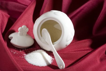 Sugar bowl, spoon and heap of sugar on red silk.の写真素材