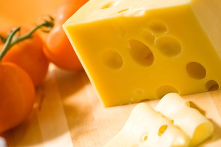 Delicious cheese on wooden desk with tomato in backgroundの写真素材