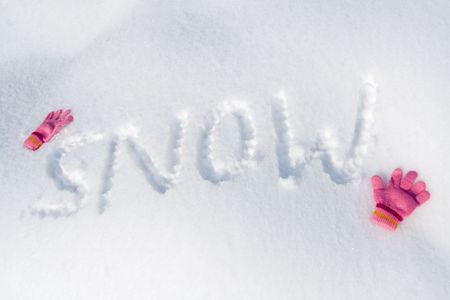 Word "SNOW" written on fresh snow, with pink gloves.の写真素材