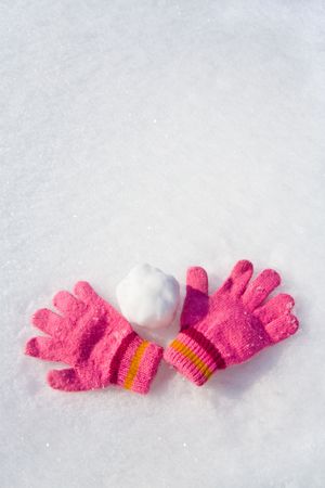 Warm female pink gloves and snowball on fresh snow.の写真素材