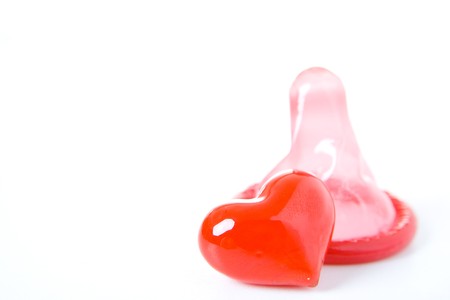 Red condom and heart isolated on white background.の写真素材