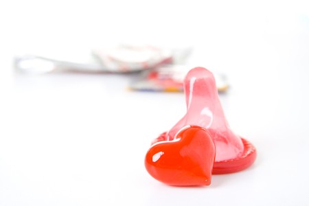 Red condom and heart isolated on white background.の写真素材