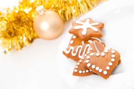 Different shaped homemade Christmas gingerbread cookies with icing and golden ribbons and bauble in...