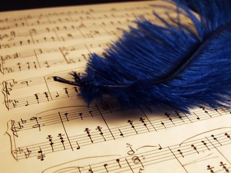 Writing notes on the yellow paper with blue featherの写真素材