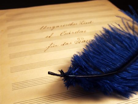 Writing notes on the yellow paper with blue featherの写真素材