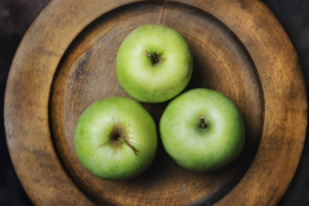 Three green apples in wooden plateの写真素材