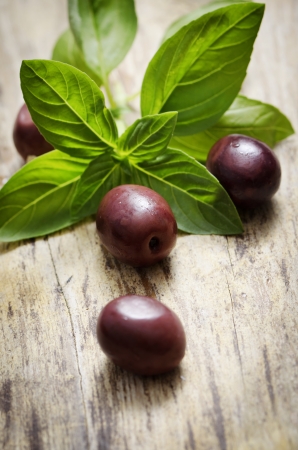 Black olives and basil on wooden tableの写真素材