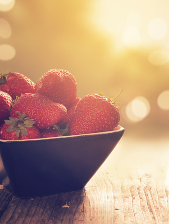 Warm sunlight falling on the bowl of strawberriesの写真素材