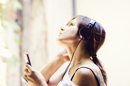 Young girl listening the music in the street.の写真素材