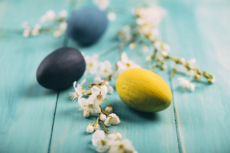 Hand painted colorful easter eggs decorated with spring cherry blossoms on wooden background.の写真素材