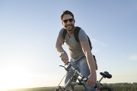 Man riding a bicycle and having outdoor fun. Summer holiday backpack adventure traveler.の写真素材