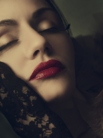 Fine art portrait of beautiful dreamy woman with fashionable makeup and red lips. Female model face closeup with luxury retro style make up and vitage laced gloves.の写真素材